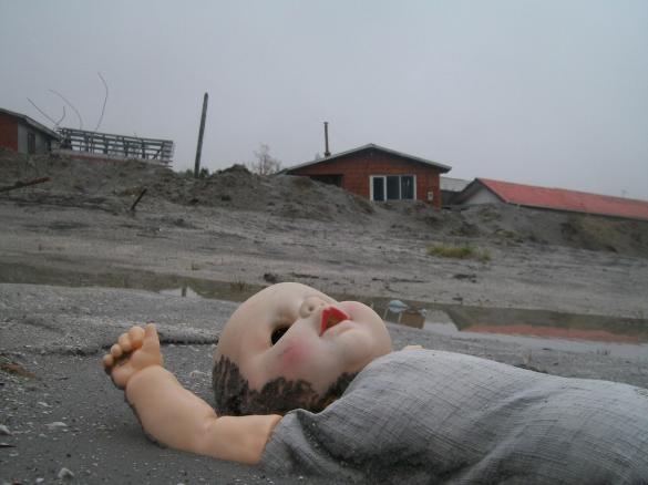 Child's doll abandoned in the ash by lopsided buildings. Child's doll abandoned in the ash by lopsided buildings.